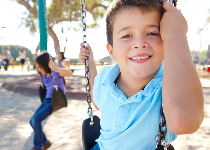 young boy smiling on a swing set