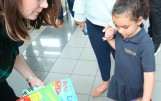 Woman holds a book. A child stands across from her.